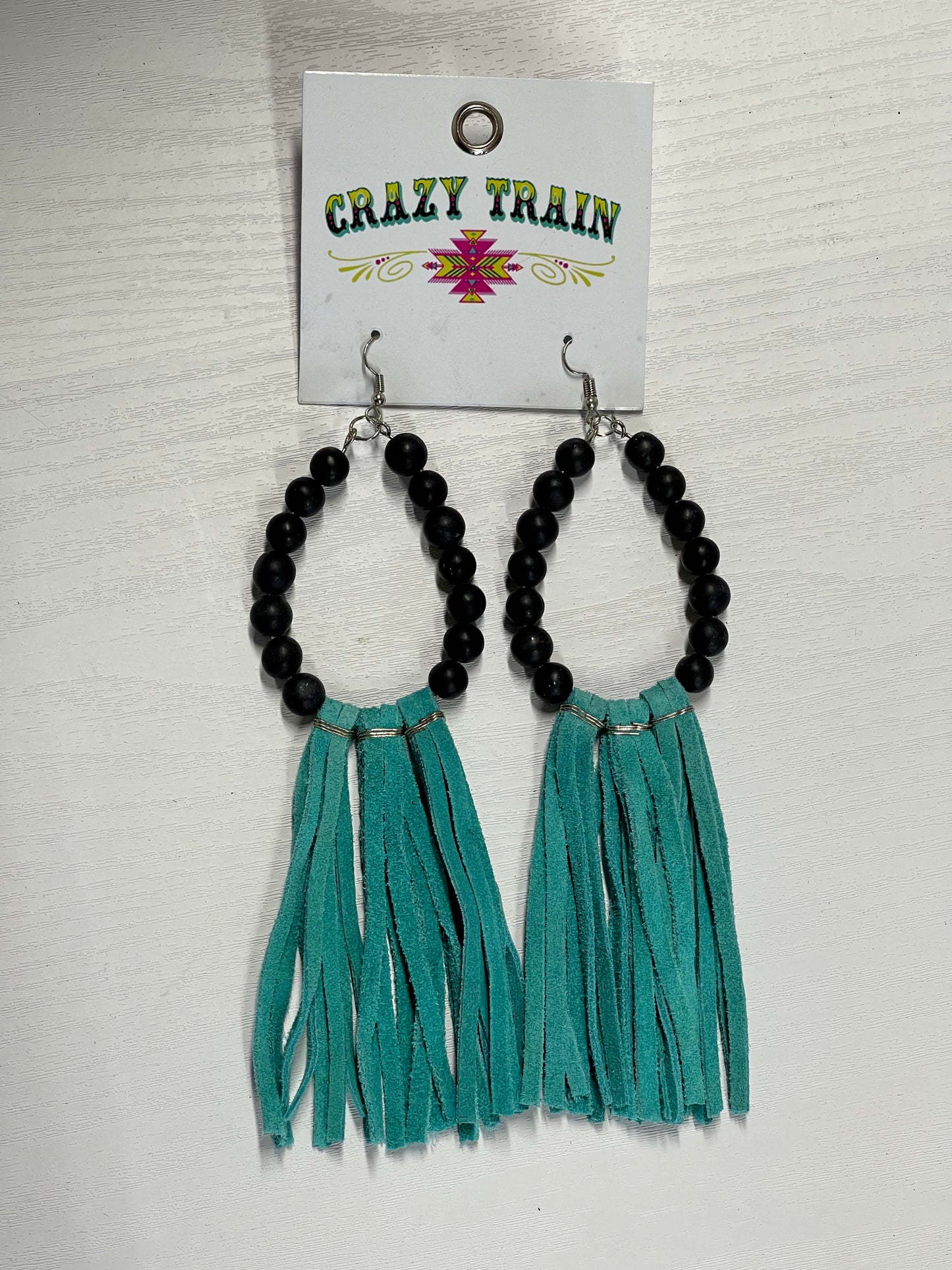 Teardrop shaped earrings with black beads lining the teardrop with teal, leather tassels along the bottom.