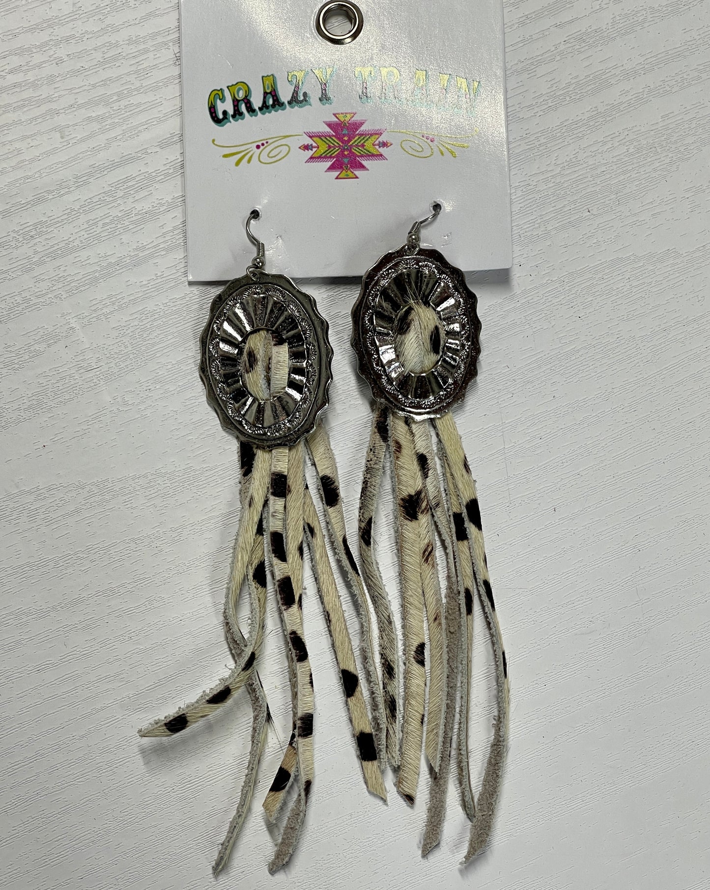 Crazy train earrings. Brown and cream cowhide printed leather tassels pulled through silver metal concho.