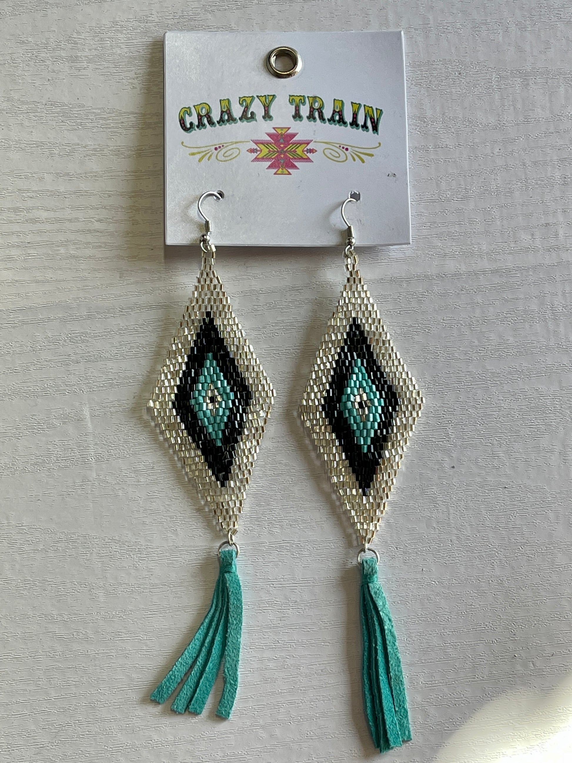 Silver, teal, and black diamond shaped earrings with teal leather tassels at the bottom.