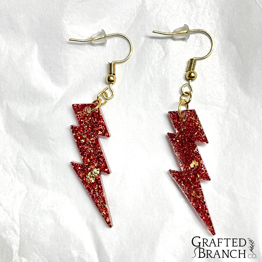 Earrings in the shape of a lightning bolt.  They are red with gold flecks and gold hooks.